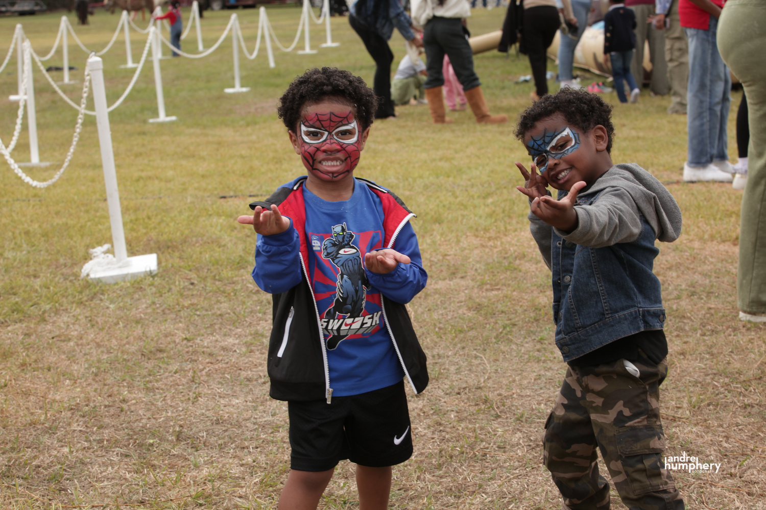 Two boys in Spider-Man face paint posing on the festival field