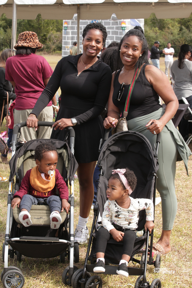 Two moms smiling with their toddlers in strollers
