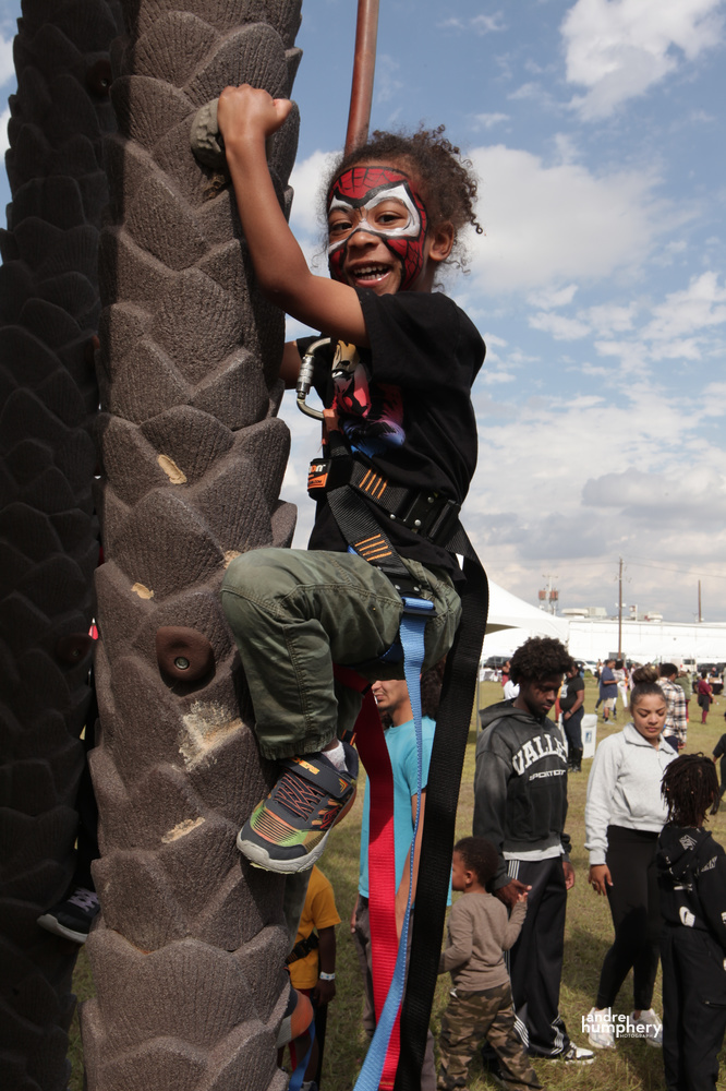 A boy in Spider-Man face paint climbing the rock wall